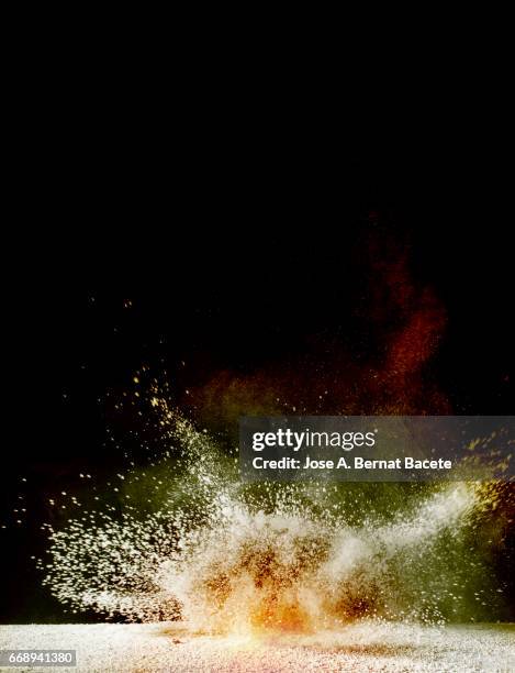 explosion of a cloud of powder of particles of yellow and red color on a black background - naturaleza muerta imagens e fotografias de stock