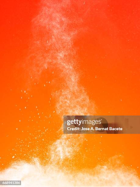 explosion of a cloud of powder of particles of white color on a orange background - naturaleza muerta imagens e fotografias de stock