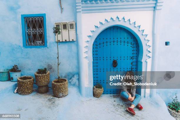 woman sitting near the doors in chefchaouen - morocco tourist stock pictures, royalty-free photos & images