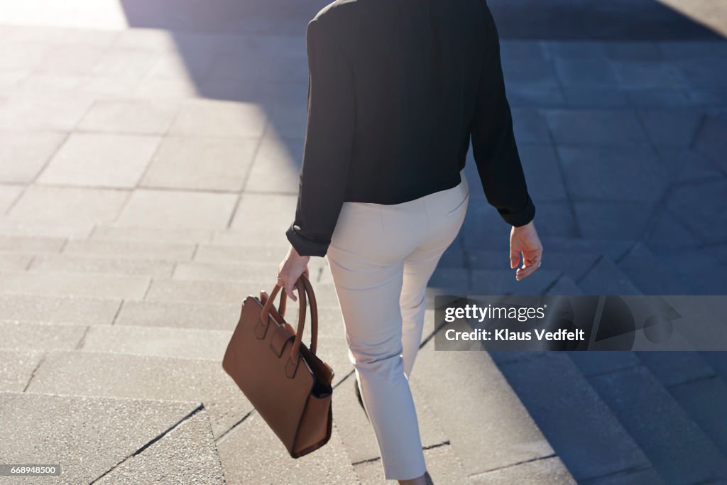 Businesswoman walking on staircase with bag
