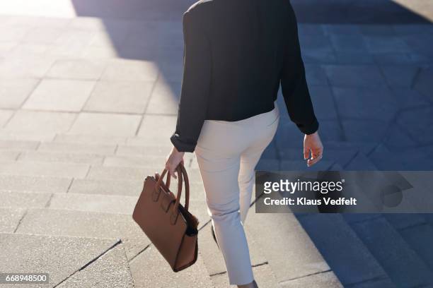 businesswoman walking on staircase with bag - business women pants stockfoto's en -beelden