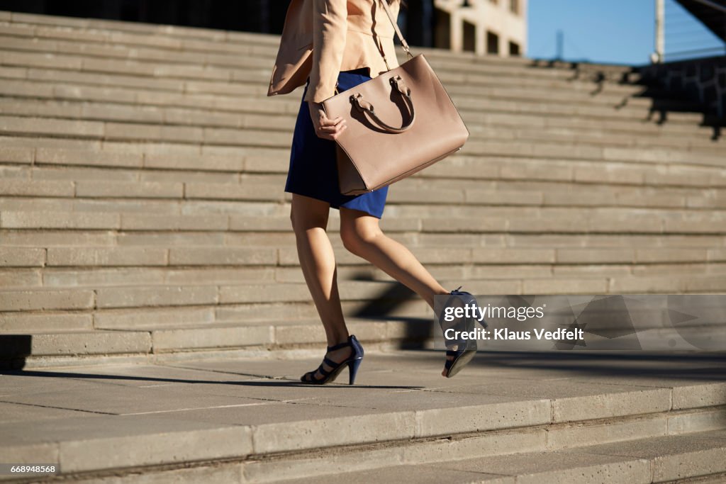 Businesswoman walking on staircase with bag
