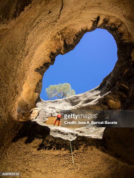 climbing speleologist, descending for the interior of a cave - agujero stockfoto's en -beelden
