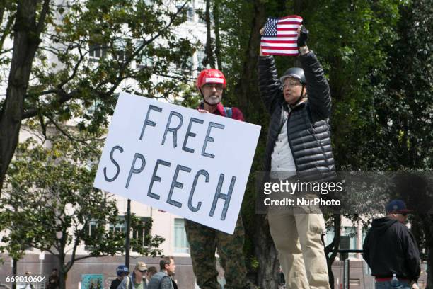 Trump supporters hold a sign and flag during a free speech rally at Martin Luther King Jr. Civic Center Park in Berkeley, California, United States...