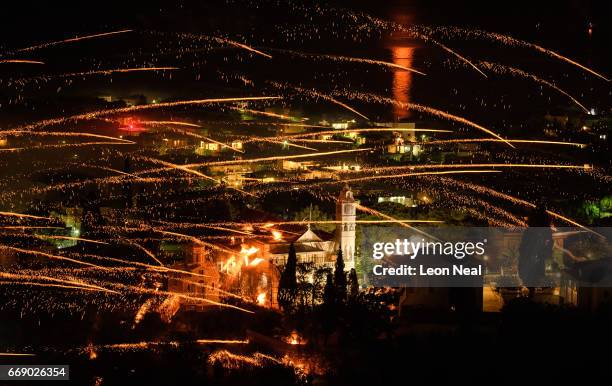 The moon is reflected in the sea as rockets are fired between the Aghios Marko Church and the Panaghia Erithiani Church during the annual Rocket War,...