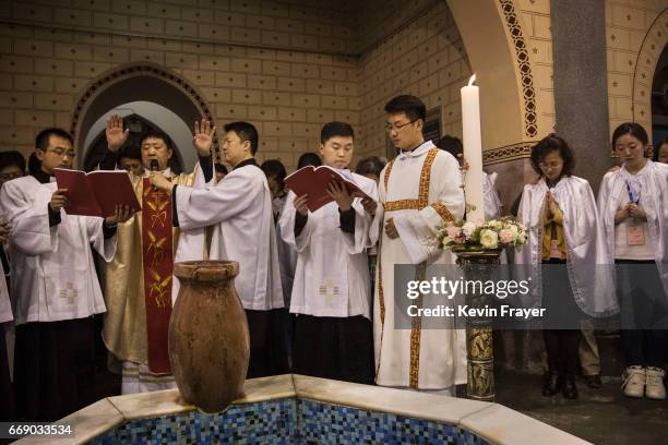 Chinese Catholic Bishop Zhang Hong, second left, leads a blessing after a special baptism ceremony at a mass on Holy Saturday during Easter...