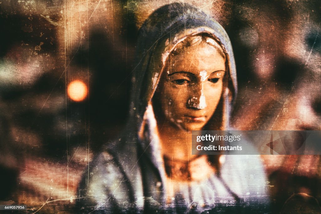 Grungy processing of an old and chipped plaster bust of Virgin Mary, one of the iconic figures of some Christian religion.