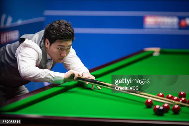 Yan Bingtao of China plays a shot during his first round match against Shaun Murphy of England on day two of Betfred World Championship 2017 at...