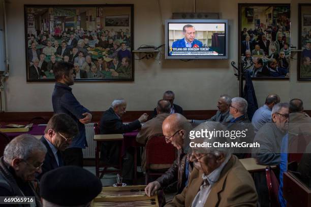 Men chat and drink chai at a teahouse while footage of Turkish President Recep Tayyip Erdogan after casting his referendum vote is seen on a tv on...