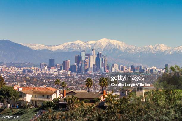 ingesneeuwd pieken bergen en downtown los angeles stadsgezicht - los angeles skyline stockfoto's en -beelden