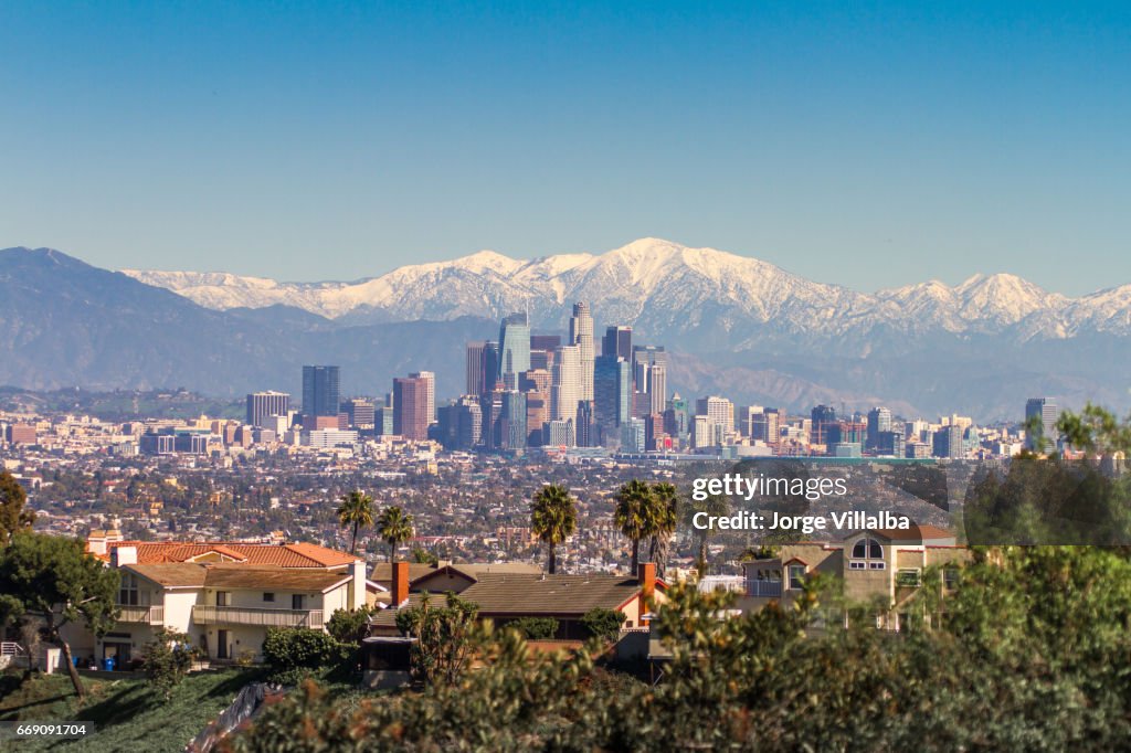 Snowed peaks mountains and downtown Los Angeles cityscape