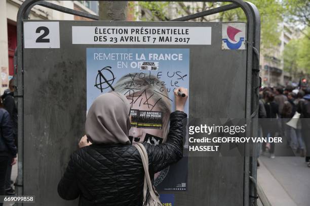 Woman writes "You thief, go see the judge" on a far-right candidate campaign poster during an anti-facist demonstration on April 16, 2017 in...