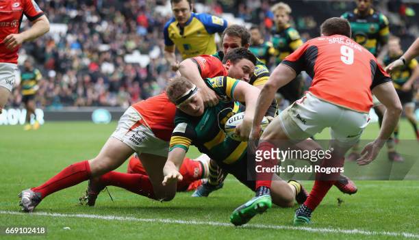 Dylan Hartley of Northampton dives over for a try despite being held by Jamie George during the Aviva Premiership match between Northampton Saints...