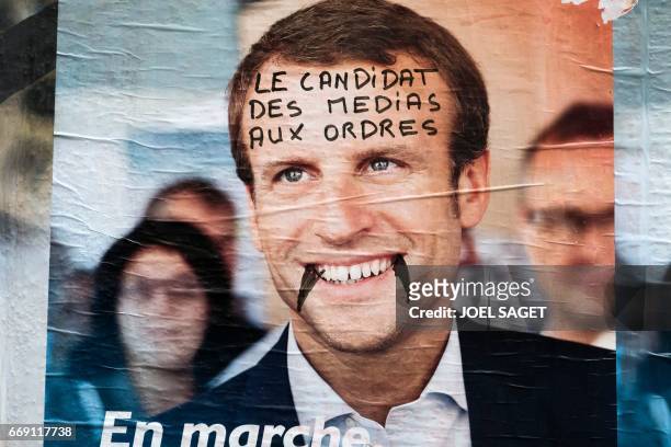 This picture taken in Paris on April 13 shows an electoral poster of French presidential election candidate for the En Marche ! movement Emmanuel...