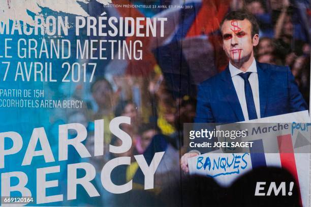 This picture taken in Paris on April 16 shows an electoral poster of French presidential election candidate for the En Marche ! movement Emmanuel...