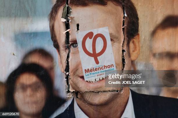 This picture taken in Paris on April 13 shows an electoral poster of French presidential election candidate for the En Marche ! movement Emmanuel...