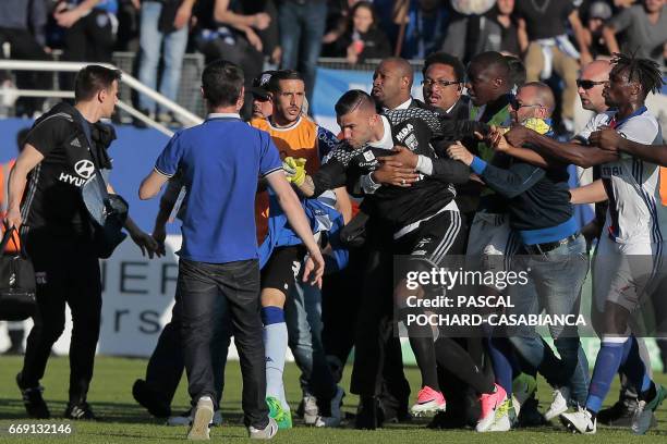 Lyon's French-Portuguese defender Anthony Lopes is held by security staff members as he clashes with Bastia's officials during the half-time the...