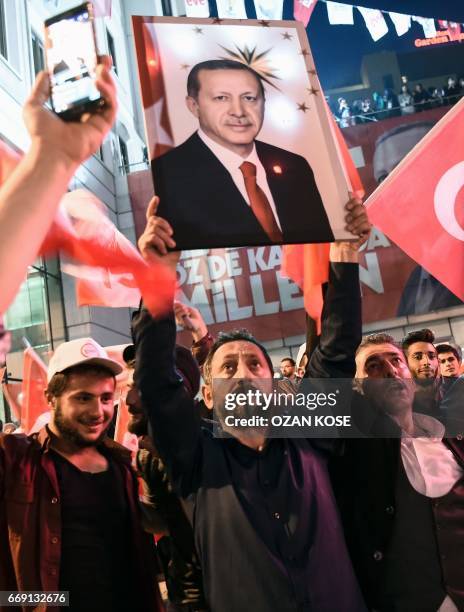 Supporter of the "yes" brandishes a picture of Turkish president Recep Tayyip Erdogan among other supporters waving Turkish national flags during a...