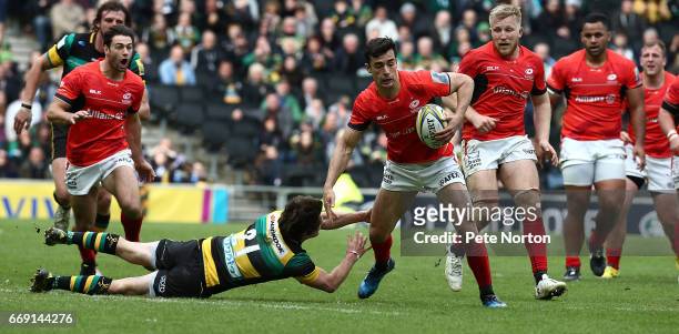 Alex Lozowski of Saracens moves forward with the ball past the challenge of Lee Dickson of Northampton Saints during the Aviva Premiership match...
