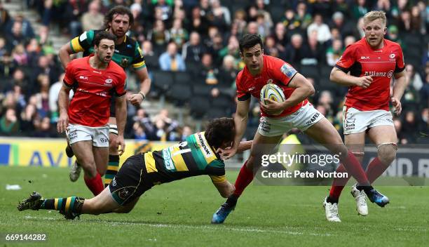 Alex Lozowski of Saracens moves forward with the ball past the challenge of Lee Dickson of Northampton Saints during the Aviva Premiership match...