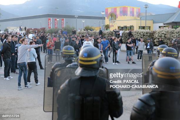 French anti-riot policemen stand guard the stadium exit as Bastia's supporters wait for the Lyon's players coach to leave after the French L1...