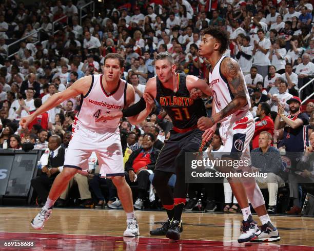 Mike Muscala of the Atlanta Hawks battles for position against Kelly Oubre Jr. #12 and Andrew Nicholson of the Washington Wizards during the Eastern...