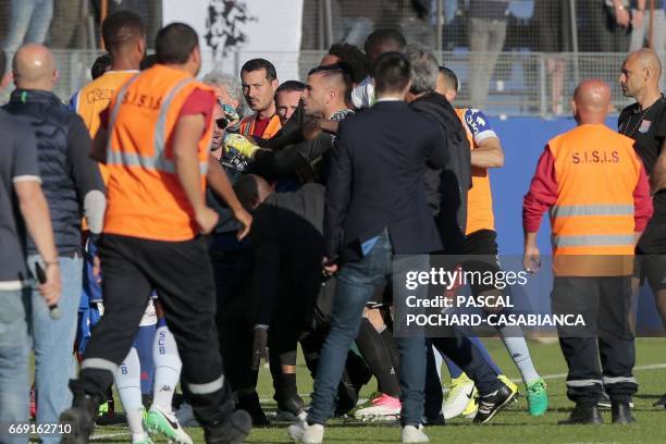 Lyon's French-Portuguese defender Anthony Lopes is held by security staff members as he clashes with Bastia's officials during the half-time the...