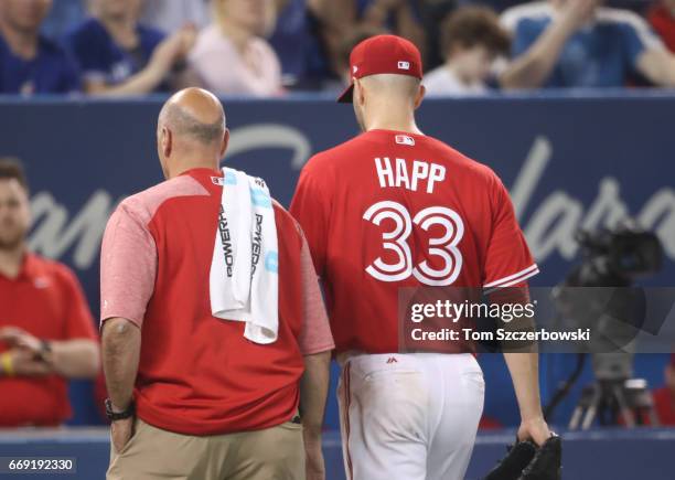 Happ of the Toronto Blue Jays exits the game with trainer George Poulos due to an arm injury in the fifth inning during MLB game action against the...