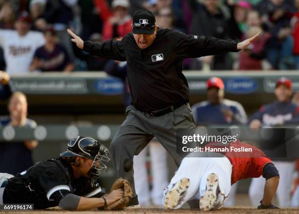 First base umpire Todd Tichenor covering the plate calls Brian Dozier of the Minnesota Twins safe on an inside-the-park home run as Kevan Smith of...