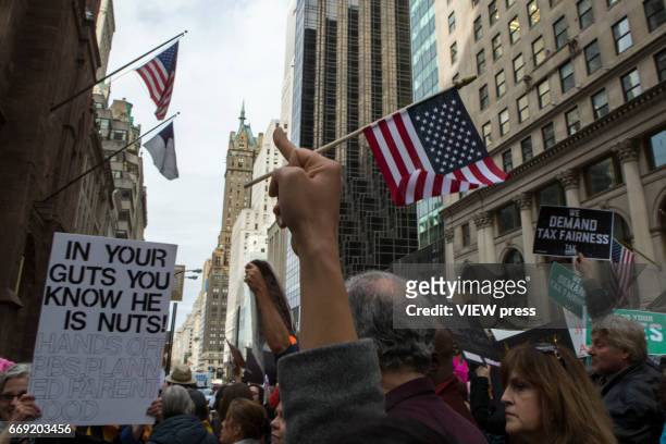 Activists raise their middle fingers as they pass near Trump Tower during a Tax Day protest on April 15, 2017 in New York City. Thousands of...