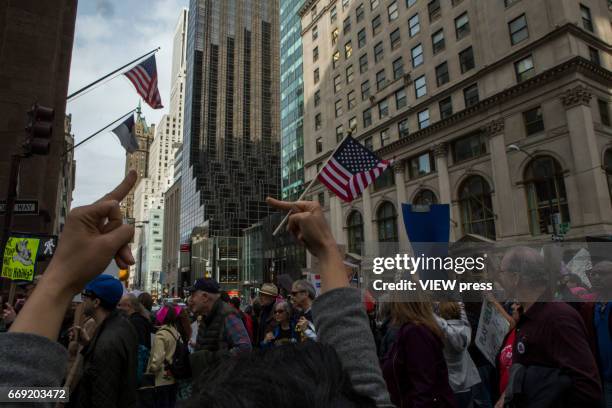 Activists raise their middle fingers as they pass near Trump Tower during a Tax Day protest on April 15, 2017 in New York City. Thousands of...