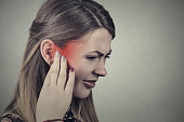 Closeup side profile sick young woman having ear pain touching her painful head temple