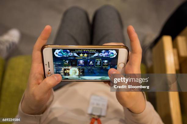An employee plays the Netmarble Games Corp. Seven Knights mobile role-playing game on a smartphone in the cafeteria at the company's headquarters in...