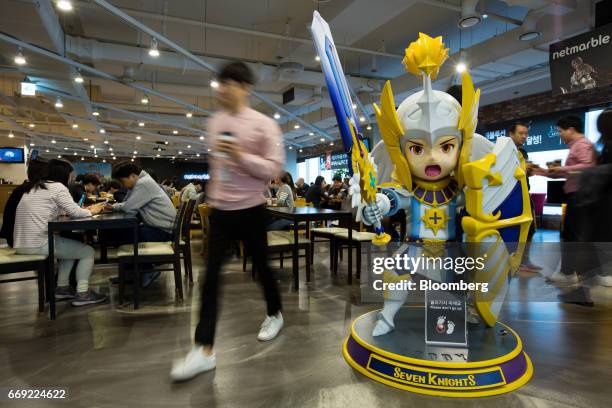 Netmarble Games Corp. Employee walks past a model figure of Rudy, a character from the Seven Knights mobile role-playing game , in the cafeteria of...