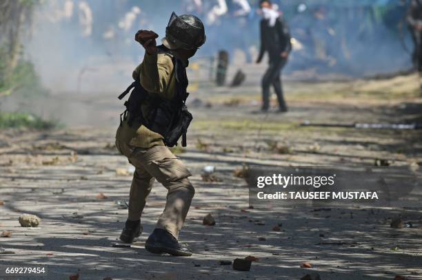 An Indian government forces throws a stone towards Kashmiri students during clashes near a college in central Srinagar's Lal Chowk on April 17, 2017....