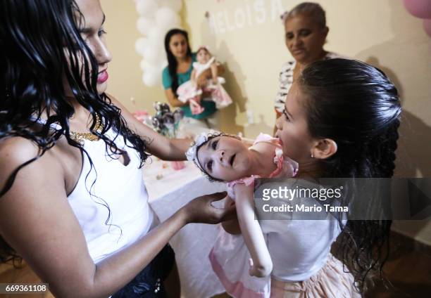 Heloa , a twin, both girls born with microcephaly, is held by celebrants at the twins' one-year birthday party on April 16, 2017 in Areia, Paraiba...