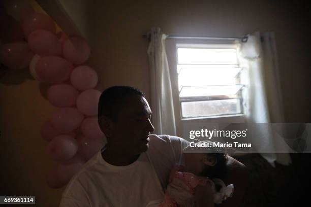 Father Marcelo holds his daughter Heloa, one of his twin daughters both born with microcephaly, at their one-year birthday party on April 16, 2017 in...