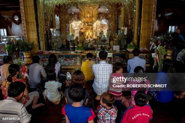 Crowd of Buddhist believers kneel down to pray in front of a statue of Lord Buddha at the Kyauktan Ye Le Pagoda, a Buddhist temple built in the...