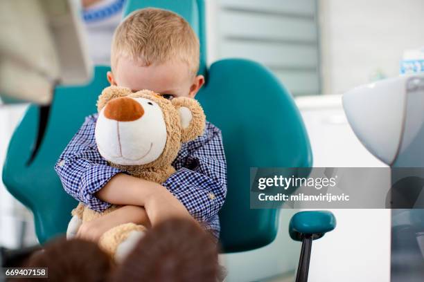liten pojke håller en nallebjörn i famnen på tandläkare kontor - tandfyllning bildbanksfoton och bilder
