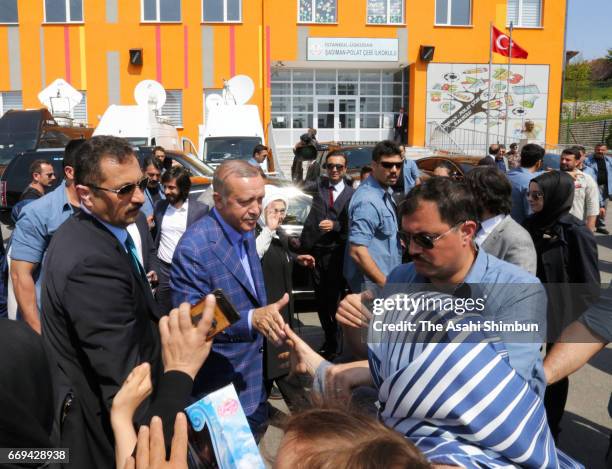 Turkish president Recep Tayyip Erdogan shakes hands with supporters after casting his ballot for the referendum at a polling station on April 16,...