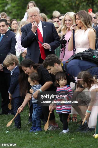 President Donald Trump and first lady Melania Trump blow whistles to kickoff a race during host the 139th Easter Egg Roll with Trump's daughter...
