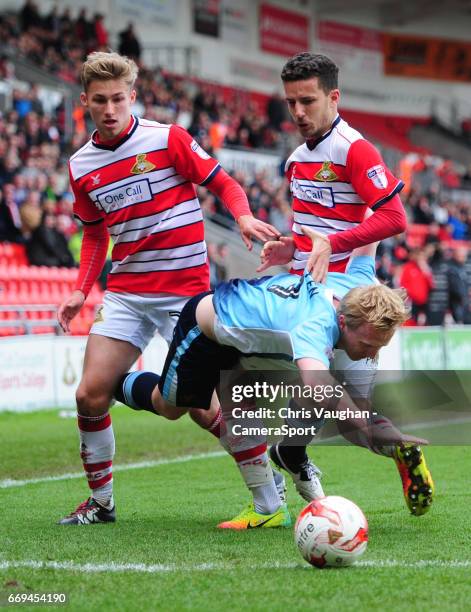 Blackpool's Mark Cullen is tackled by Doncaster Rovers' Will Longbottom, left, and Doncaster Rovers' Mathieu Baudry during the Sky Bet League Two...