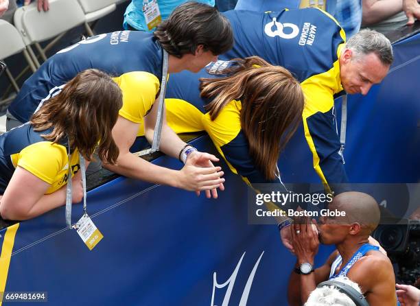 American runner Meb Keflezighi kisses the hand of Denise Richard as other members of the Richard family, from left, Jane, Henry and Bill, reach out...