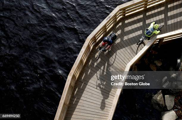 Bicyclist casts a long shadow as they cross the Charles River along the esplanade underneath the BU Bridge in Boston on Apr. 13, 2017.