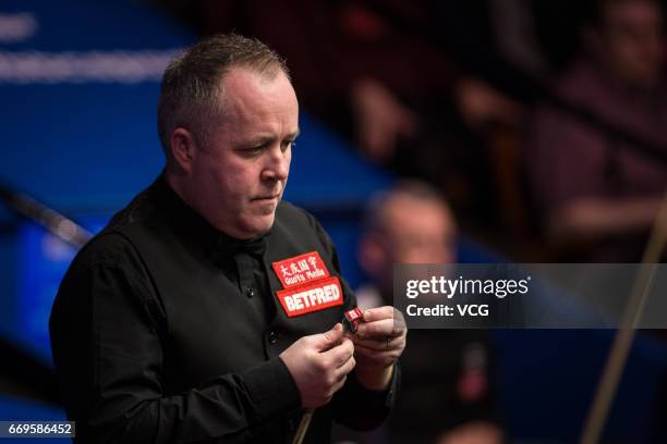 John Higgins of Scotland chalks the cue during his first round match against Martin Gould of England on day three of Betfred World Championship 2017...
