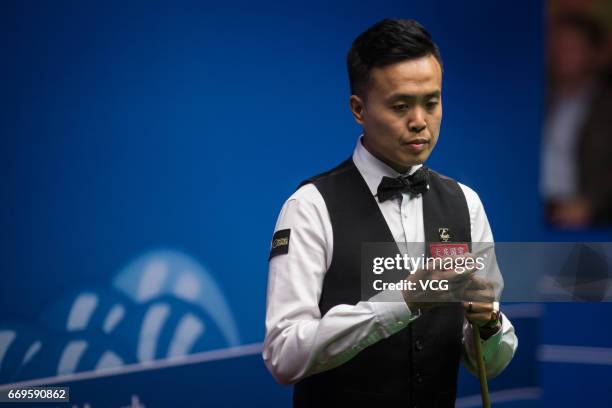 Marco Fu of Chinese Hong Kong chalks the cue during his first round match against Luca Brecel of Belgium on day three of Betfred World Championship...