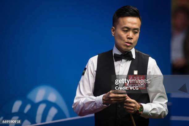 Marco Fu of Chinese Hong Kong chalks the cue during his first round match against Luca Brecel of Belgium on day three of Betfred World Championship...