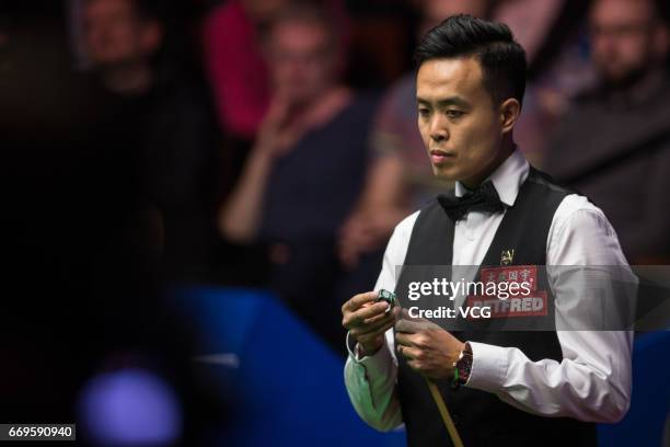 Marco Fu of Chinese Hong Kong chalks the cue during his first round match against Luca Brecel of Belgium on day three of Betfred World Championship...