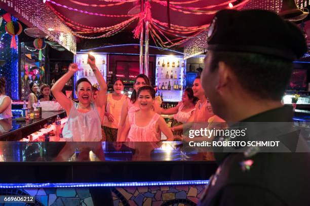 This photo taken on March 29, 2017 shows Thai Police Lieutenant Colonel Sulasak Kalokwilas interacting with bartenders at an outside bar as he...