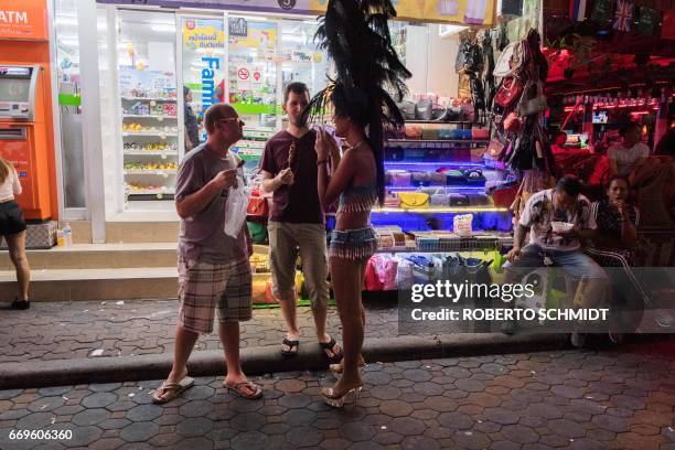 This photo taken on March 29, 2017 shows two foreign tourists standing in front of a stall selling handbags in Walking Street in Pattaya. Two hours...